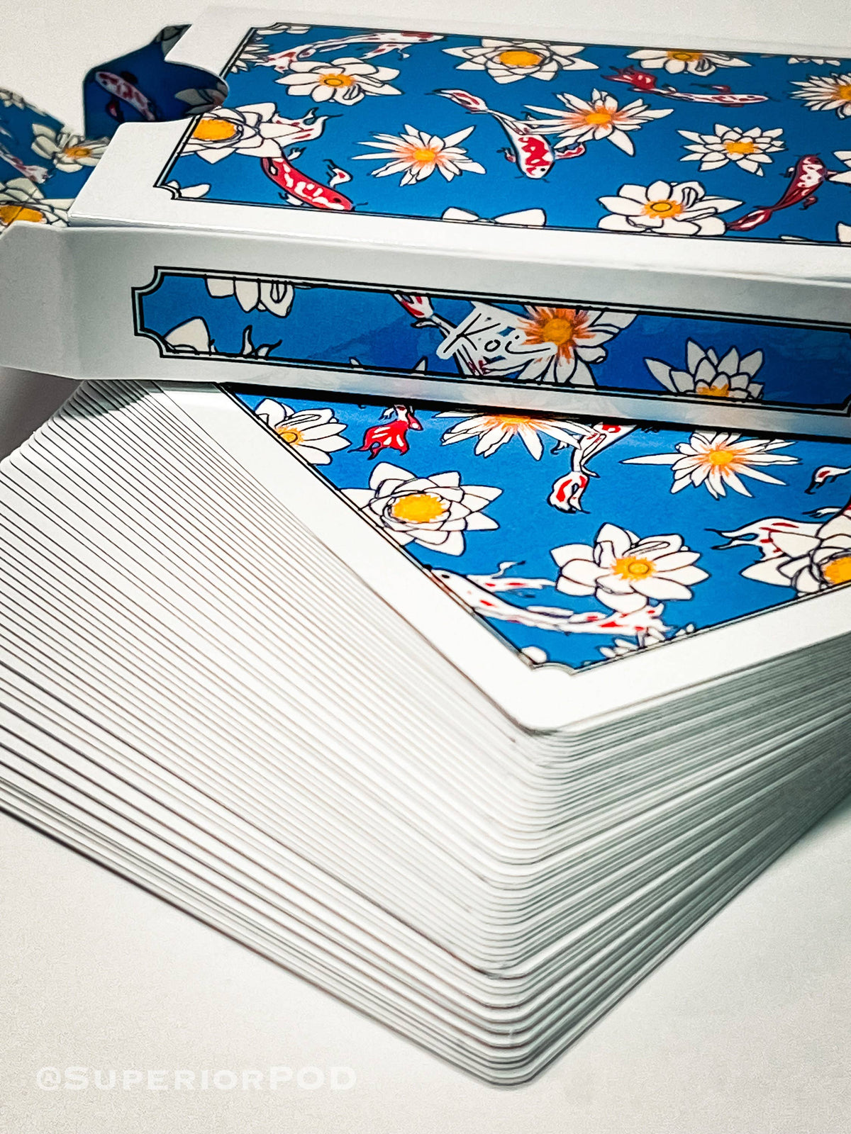 Close-up of blue playing card backs decorated with koi fish and white lotus flowers