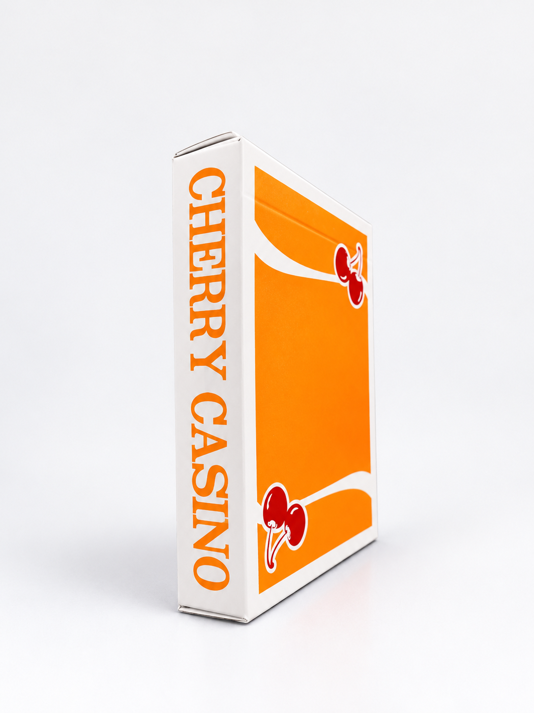 Angled side view of Cherry Casino Summerlin Sunset Orange Playing Cards showing the white tuck box, vibrant orange cherry artwork and Cherry Casino lettering along the side.