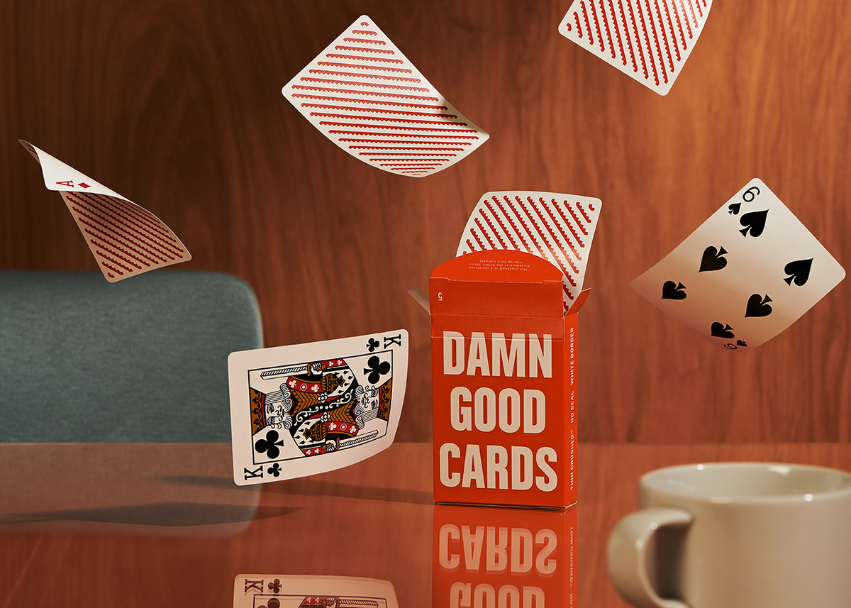 Damn Good Cards No. 5 by Dan & Dave displayed with orange geometric card backs, traditional playing card faces and orange tuck box on a wooden table.