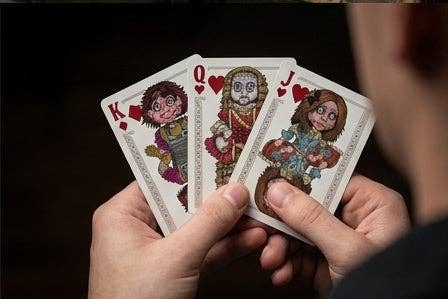 Haunted Dolls Playing Cards by CPC showing the King, Queen and Jack of Diamonds with creepy illustrated doll characters, held in a player's hands.