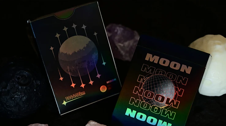 Moon Black Holo Playing Cards by Hiddenlight showing the front and back of the black holographic tuck box, featuring rainbow MOON lettering, a central wireframe sphere and colourful lunar artwork.