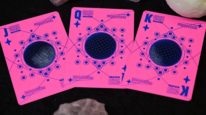Moon Pink Standard Playing Cards by Hiddenlight showing custom Jack, Queen and King court cards with vibrant neon pink backgrounds, dark blue geometric patterns and distinctive lunar-inspired artwork.