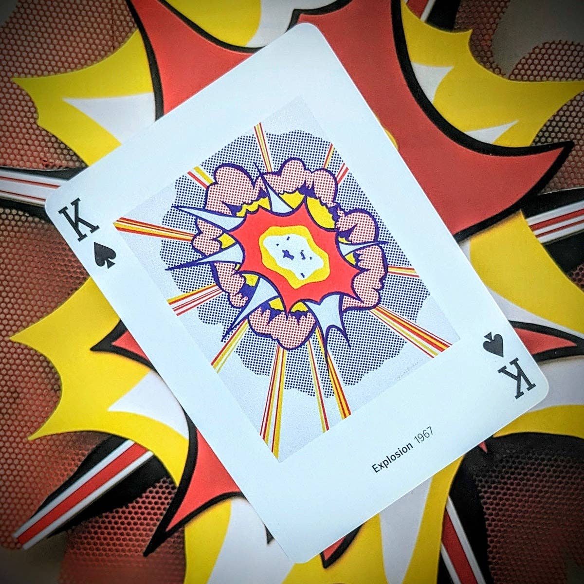 Piatnik Roy Lichtenstein Playing Cards featuring the King of Spades illustrated with the Pop Art artwork Explosion 1967, against a colourful comic-style background.