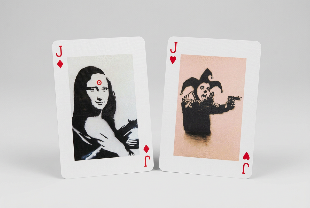 Piatnik More Banksy playing cards showing the jack of diamonds with armed Mona Lisa artwork and jack of hearts with a jester holding pistols
