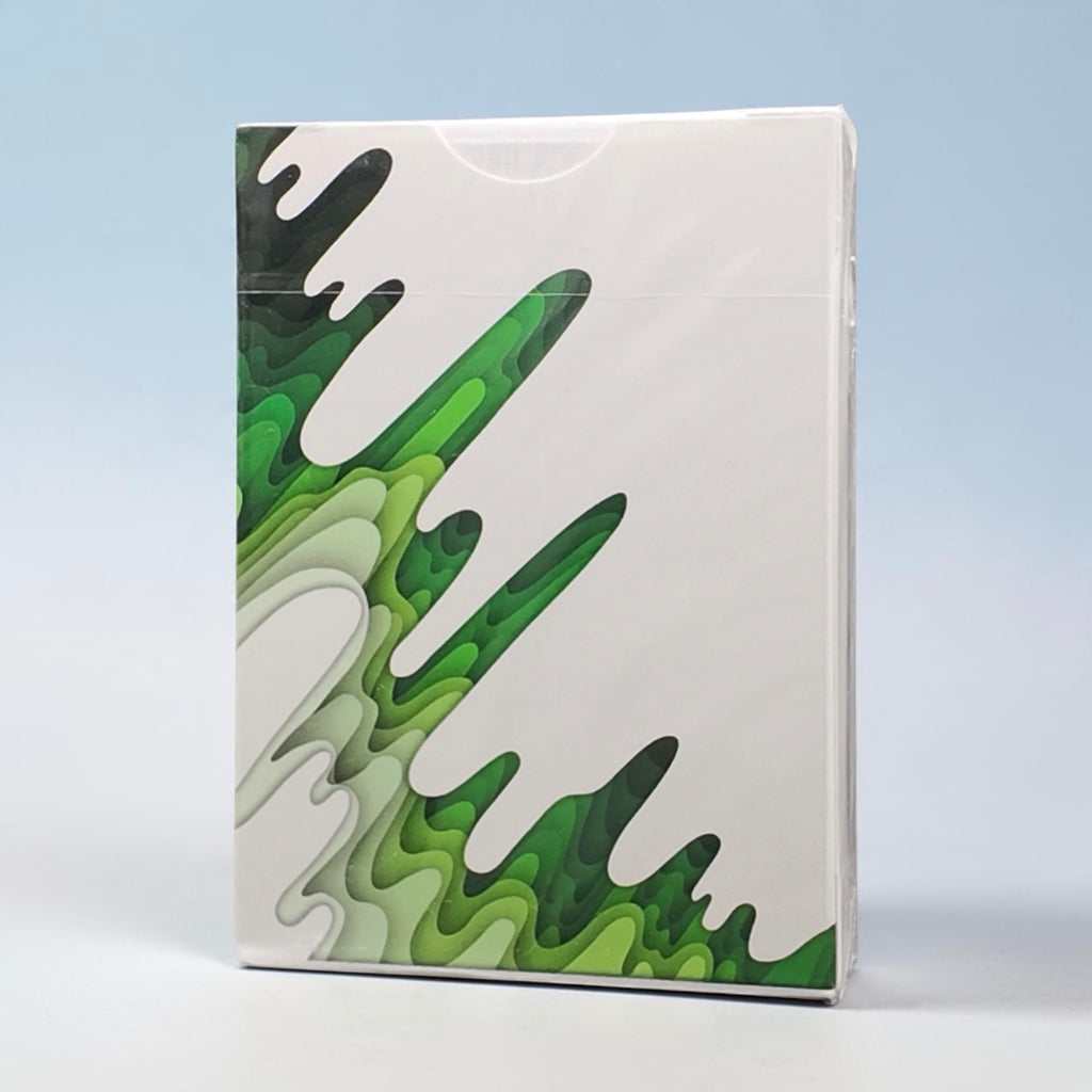 SIRIUS-B V4 Spring Edition Playing Cards by Riffle Shuffle, with a glossy finish, featuring an abstract green and black paint drip design on the left side, photographed against a light blue gradient background.