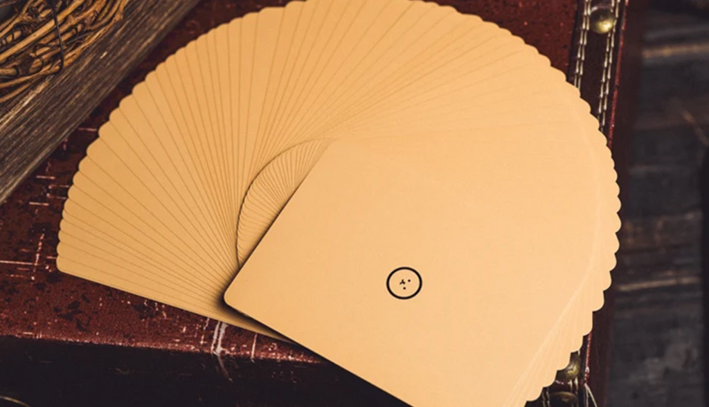 WHIKO Stage Thin Playing Cards by Bacon Magic displayed in a wide fan, showing the cream-coloured card backs with a minimalist black WHIKO character emblem, designed for stage magic and card manipulation.