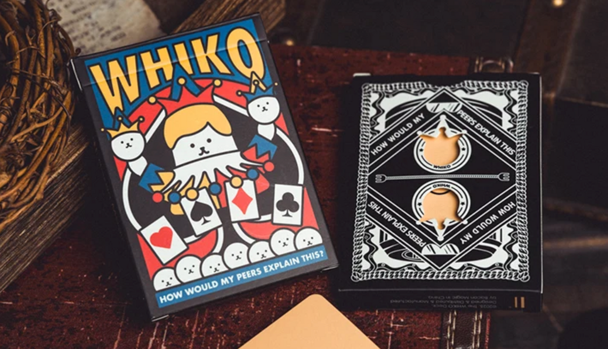 WHIKO Stage Thin Playing Cards by Bacon Magic showing the colourful cartoon jester tuck box alongside the black and white card back design, displayed on a wooden surface.